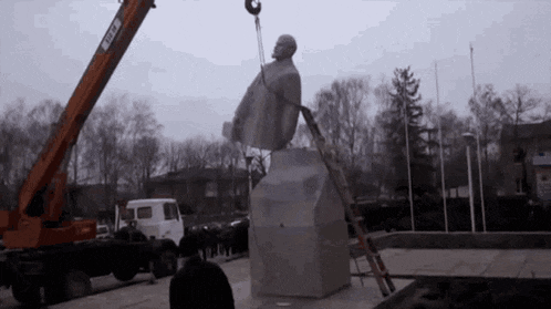 a statue of a man is being lifted by a crane that says ' cccp ' on the side