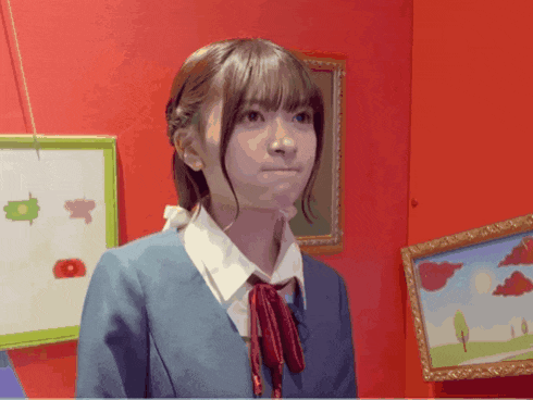 a girl in a blue jacket and red tie stands in front of a red wall with paintings on it