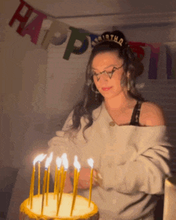a woman blowing out candles on a birthday cake