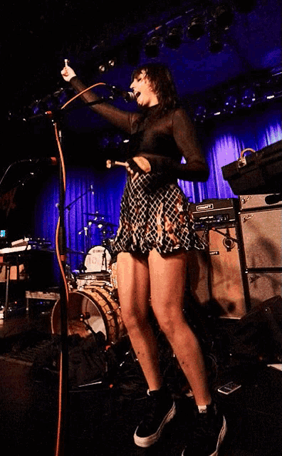 a woman singing into a microphone while wearing shorts