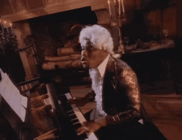 a man in a wig is playing a piano in front of candles