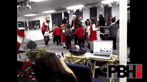 a woman is taking a picture of a group of children dancing in front of a laptop and a sign that says pbh