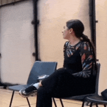 a woman is sitting on a chair with her legs crossed in a gym .