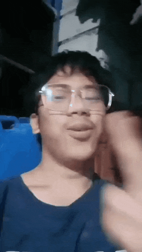 a young boy wearing glasses and a blue shirt is making a funny face .