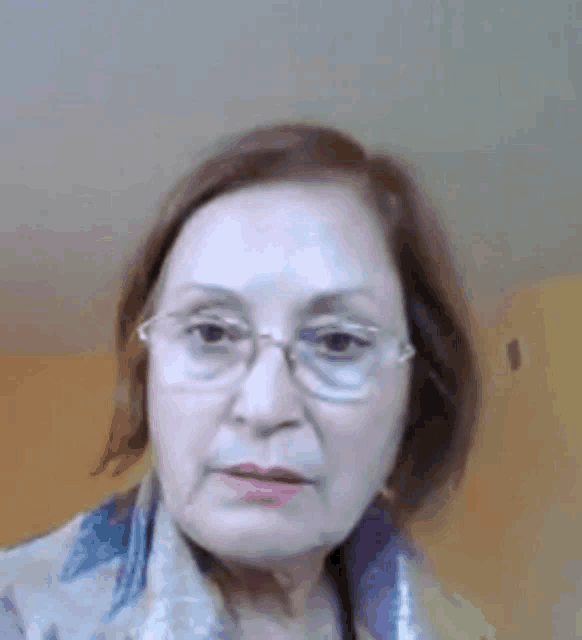 a woman wearing glasses and a scarf looks at the camera .