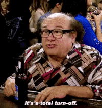 a man with glasses is sitting at a table with a bottle of beer and says it 's a total turn-off