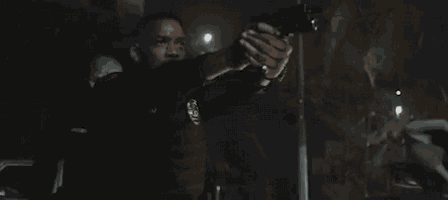 a man in a police uniform is pointing a gun at someone in a dark room .