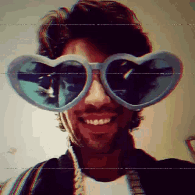 a man wearing heart shaped sunglasses is smiling for the camera