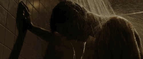 a man is taking a shower in a bathroom with water coming out of his head .