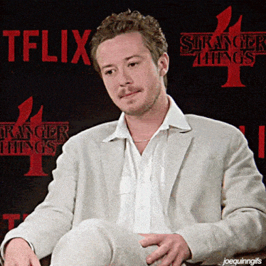 a man sitting in front of a sign that says stranger things