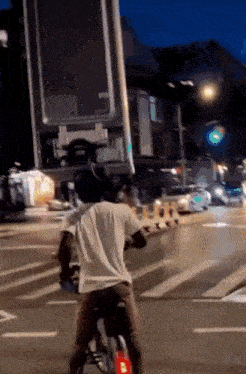 a man is riding a bicycle down a street at night