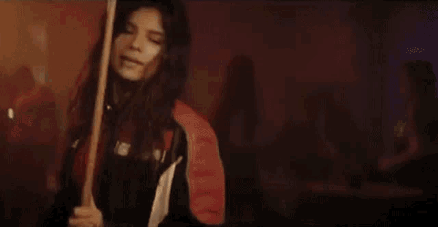 a woman in a red top and black jacket is holding a pool cue .
