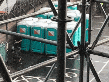a man squatting in front of a row of portable toilets with a handicap sign