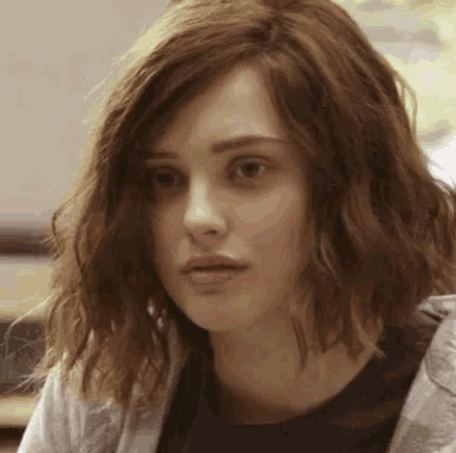 a close up of a young woman 's face with short wavy hair .