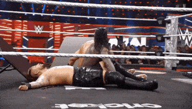a man is laying on the ground in a wrestling ring with the word cricket on the floor .