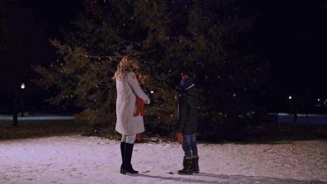 a woman and a child looking at a christmas tree