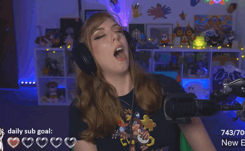 a woman wearing headphones making a funny face in front of a microphone with a daily sub goal of 743/70