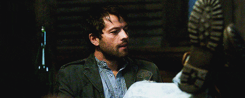 a man with a beard is sitting in a chair in a dark room looking at something .