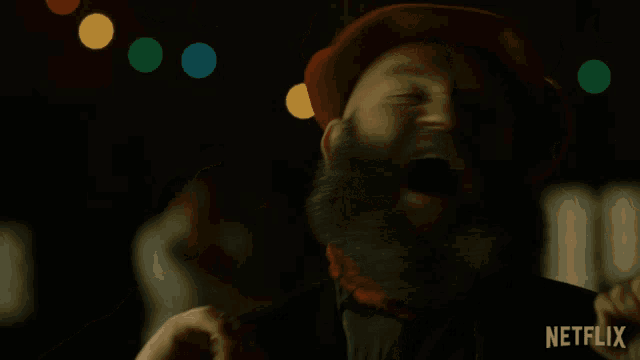 a man with a beard wearing a red hat and a scarf has a netflix logo on the bottom right