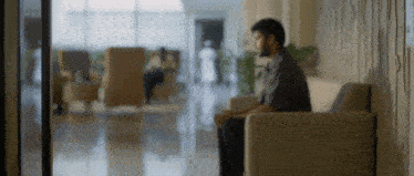 a man is sitting on a couch in a hallway in a hospital waiting room .