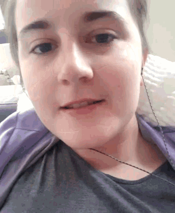 a close up of a person 's face with a purple shirt on