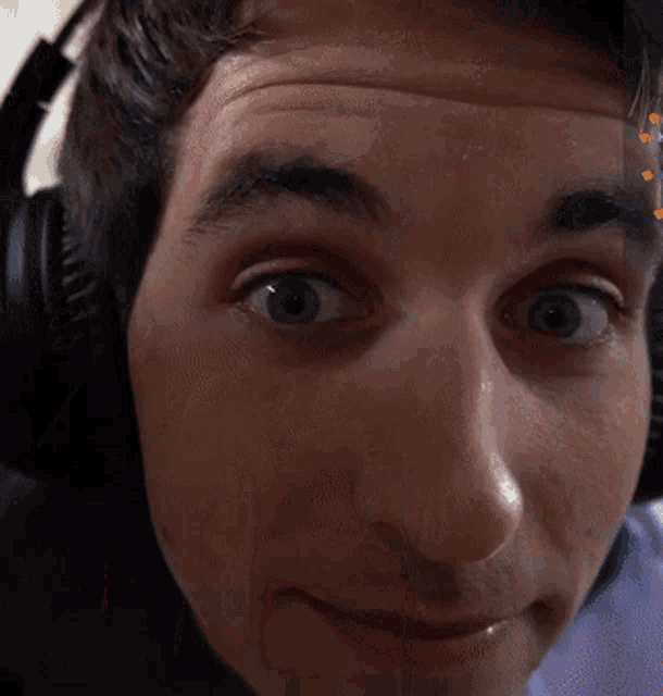 a man wearing headphones looks at the camera with a surprised look on his face