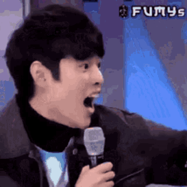 a young man is holding a microphone in his hand and making a funny face .