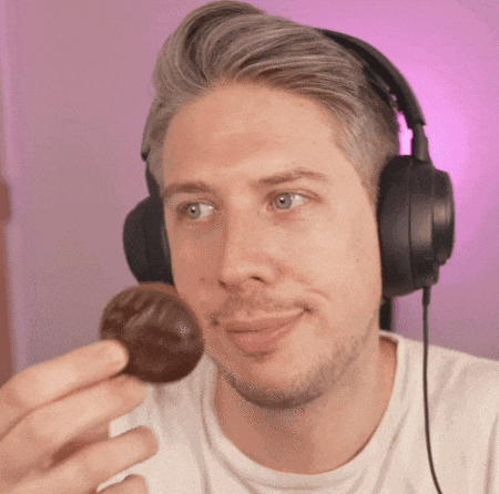 a man wearing headphones is eating a chocolate covered ball