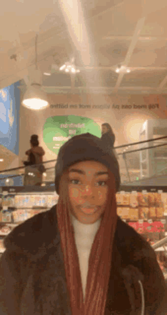 a woman wearing a black hat and scarf stands in front of a sign that says ' netflix ' on it
