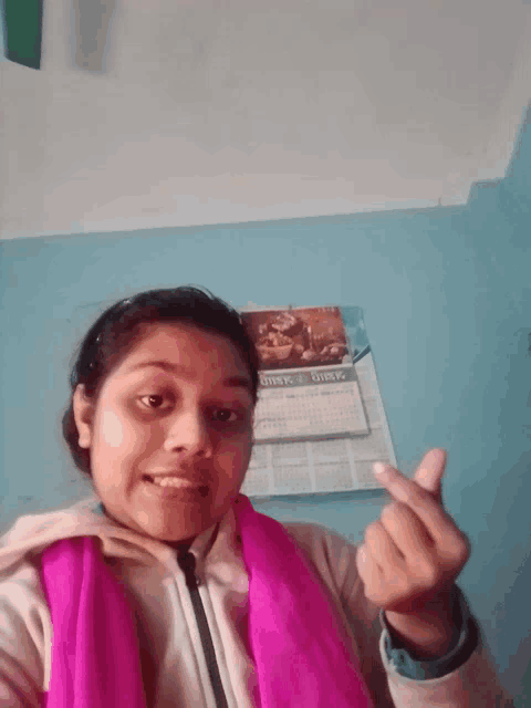 a girl making a heart shape with her fingers in front of a wall calendar that says stock girls