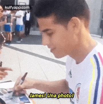 a man in a white shirt is signing a picture for a fan .