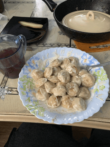 a plate of dumplings sits on a table next to a cup of tea