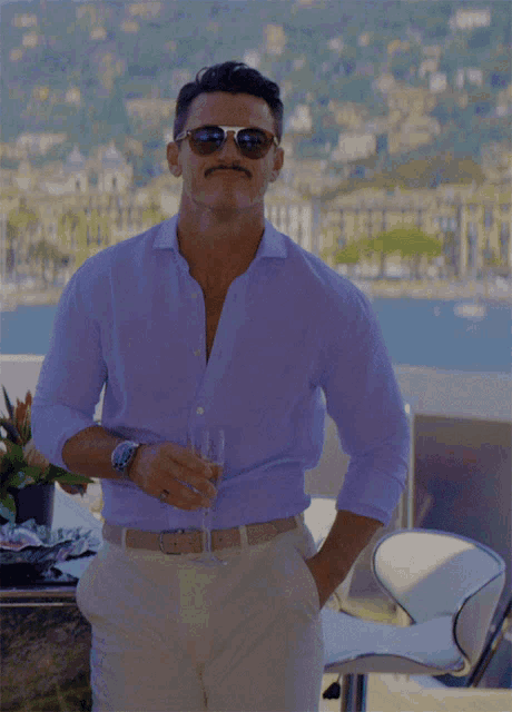 a man wearing sunglasses and a mustache is holding a glass of wine