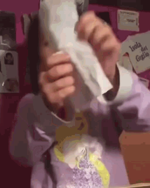 a person is holding a piece of paper over their face .
