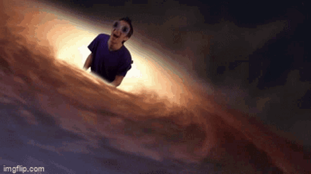 a man in a purple shirt and goggles is standing in front of a black hole .