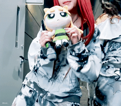 a woman with red hair holds a stuffed animal in her hands