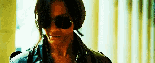 a close up of a person wearing sunglasses and a cigarette .