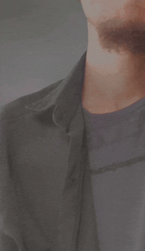 a man with a beard is wearing a gray shirt
