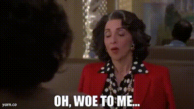 a woman in a red jacket and polka dot shirt is talking to a man in a restaurant .