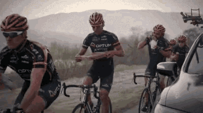 a group of cyclists are riding down a road and one of them is wearing a shirt that says optum