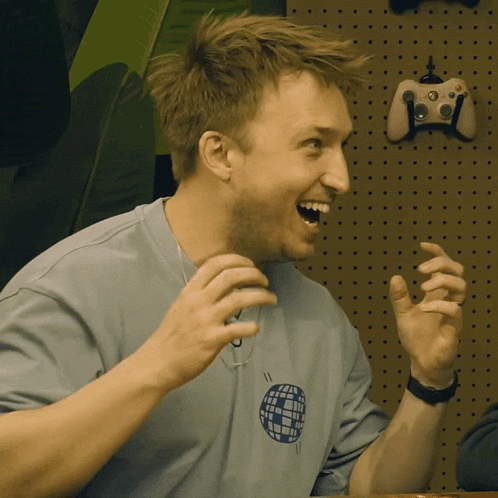 a man wearing a blue shirt with a globe on it laughs