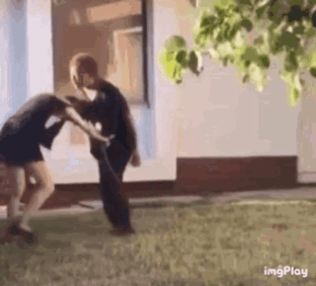 a man and a woman are fighting in a yard .