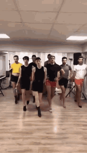 a group of men are dancing in a room and one of them is wearing a t-shirt that says fight club