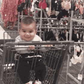 a baby is sitting in a shopping cart and smiling