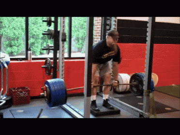 a man lifts a barbell in a gym wearing a shirt that says ' warriors '