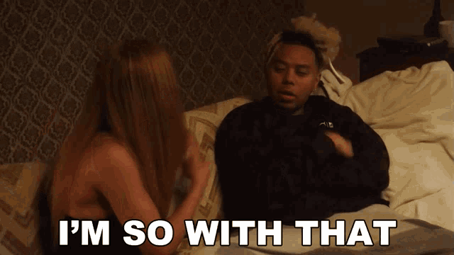 a man and a woman are laying in bed and the man says i 'm so with that