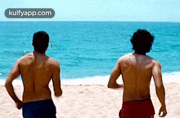 two shirtless men are running on a beach with the words kulfyapp.com visible in the corner