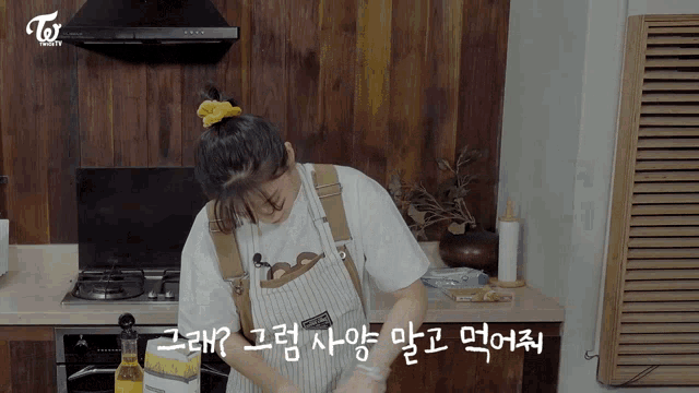 a woman in an apron is cooking in a kitchen with korean writing on the counter