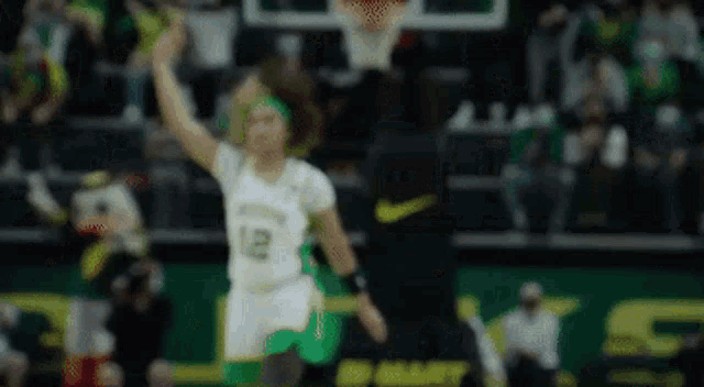 a blurred image of a woman playing basketball on a court with a crowd in the background .