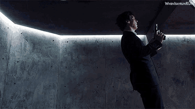 a man in a suit is holding a gun in front of a wall that says when i say run run